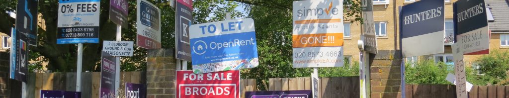 Estate agent boards showing homes to let and houses for sale